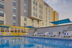 a pool with chairs and umbrellas in front of a hotel at City Express by Marriott Ensenada in Ensenada