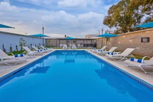 a swimming pool with chairs and umbrellas at City Express by Marriott Ensenada in Ensenada