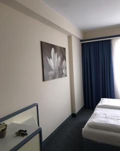 Parkhotel Schotten في شوتن: غرفة في الفندق بها سرير و صورة زهرة على الحائط