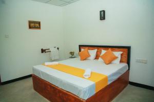 a bedroom with a large bed with orange and white pillows at Samee Dream Guest in Midigama East