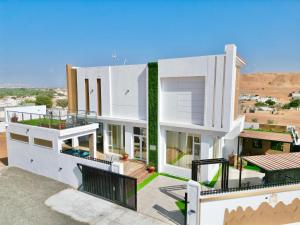 a view of a white house with a balcony at R61 Sunset Chalet in Muntarib