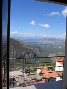 een raam met uitzicht op een stad met bergen bij THOLOS HOTEL in Delfoi