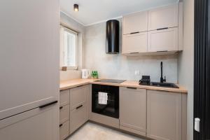 a kitchen with white cabinets and a stove top oven at Kairos Apartments - New York Premium- darmowy parking, ścisłe centrum, Spodek in Katowice