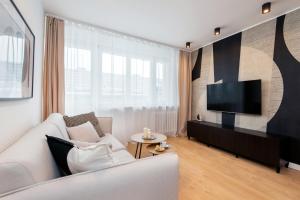uma sala de estar com um sofá branco e uma televisão de ecrã plano em Apartament New York Premium- ścisłe centrum - by Kairos Apartments em Katowice