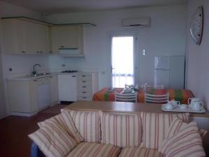 een woonkamer met een bank en een keuken bij I TORRINI DELLA PELOSA in Stintino