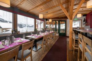 restauracja z drewnianymi sufitami, stołami i krzesłami w obiekcie Austria Alpinhotel w mieście Obertauern