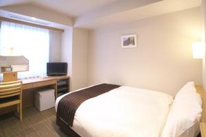 横手市にある横手プラザホテルのベッド、デスク、コンピュータが備わるホテルルームです。