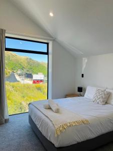 een slaapkamer met een groot bed en een groot raam bij Stunning Lakeview Holiday House Queenstown in Frankton