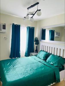 a bedroom with a green bed with blue curtains at COZYTEL Centro in Davao City