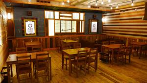 ein Restaurant mit Holztischen, Stühlen und Fenstern in der Unterkunft Shibu Onsen Koishiya Ryokan in Yamanouchi
