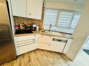 a kitchen with white cabinets and a sink at Maison d'hôtes à 2 pas de Paris in Les Lilas