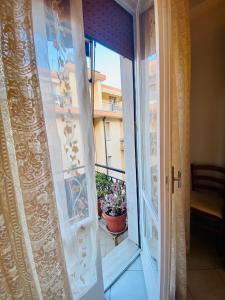 a sliding glass door with a pot of flowers on a balcony at Hostdomus - La casina di Monica in Loano