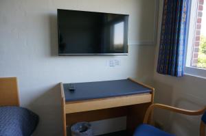 een kamer met een tv aan de muur en een bureau bij Motel Spar 10 in Viborg