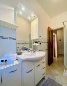 a white bathroom with a sink and a mirror at Hostdomus - La casina di Monica in Loano