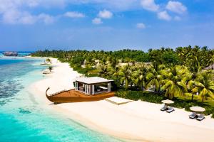 a boat on a beach with palm trees and the ocean at OZEN RESERVE BOLIFUSHI - Luxury All Inclusive in Male City
