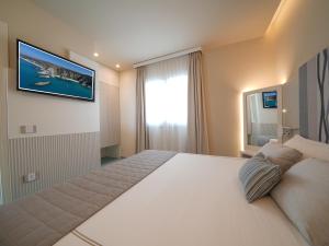 a bedroom with a large bed with a television on the wall at Hotel Village Eden in Capo Vaticano
