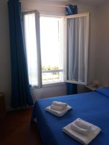 een slaapkamer met 2 handdoeken op een bed met een raam bij I TORRINI DELLA PELOSA in Stintino