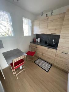 cocina con armarios de madera, mesa y sillas rojas en Villa Le Paradis en Pern