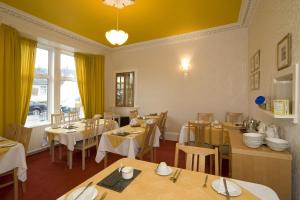 een restaurant met tafels en stoelen en een geel plafond bij St Annes Guest House in Oban