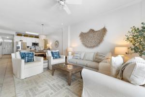 sala de estar con muebles blancos y cocina en Grand Pointe 401 en Orange Beach