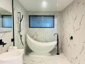 ein weißes Badezimmer mit einer Badewanne und einem Waschbecken in der Unterkunft Stunning Lakeview Holiday House Queenstown in Frankton