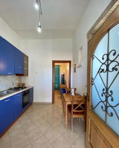 cocina y comedor con mesa y armarios azules en Casa Vacanze Torre di Mola, en Formia