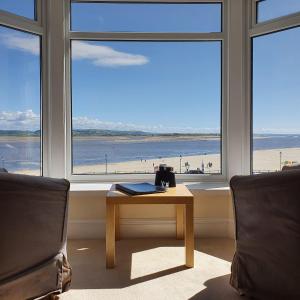 a room with a table and a view of the beach at Fron Haul in Aberdyfi