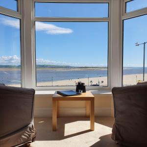 a living room with a table and a view of the beach at Fron Haul in Aberdyfi