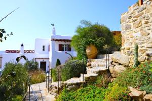 a white house with stairs and a stone wall at VILLA NAUTILIA - Luxury Suites and Cottages in Kalafatis