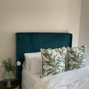 a bed with a blue headboard and pillows on it at Contemporary unit at the Blyde in Pretoria