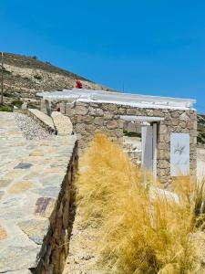 a stone building with a roof on a hill at Milo Milo Suites in Mandrakia