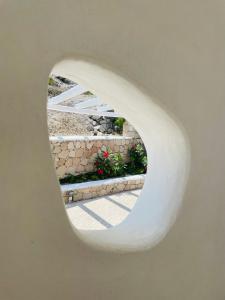 a circular window in a white wall with flowers in a garden at Milo Milo Suites in Mandrakia