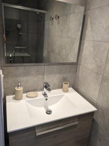 La salle de bains est pourvue d'un lavabo blanc et d'un miroir. dans l'établissement T2 bord de mer avec garage, à Collioure