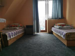 two beds in a room with a window at Domek u Stocha in Poronin