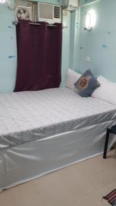 1 dormitorio con 1 cama blanca grande con cortina morada en Relaince lucky home, en Hong Kong