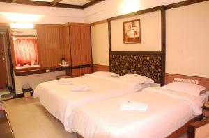 two beds in a hotel room with white sheets at Hotel Blue Star in Coimbatore