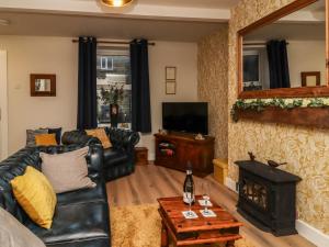- un salon avec un canapé en cuir noir et une cheminée dans l'établissement The Robins Holiday Cottage, à Keighley