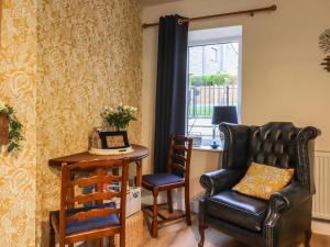 - un salon avec une chaise, une table et une fenêtre dans l'établissement The Robins Holiday Cottage, à Keighley