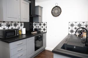 a kitchen with a sink and a microwave at The Nook Cottage, Parkgate, Wirral in Parkgate