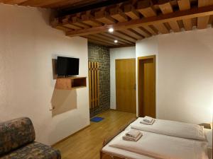 Habitación con cama y TV en la pared. en Gasthof Paluda - Pizzeria, en Dalaas