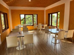 a dining room with tables and chairs and windows at Bel-Air Ayurveda Resort in Panchgani
