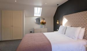 a bedroom with a large white bed and a mirror at Hoglet Cottage in Carlisle