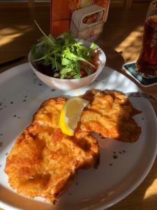 un plato de comida con pescado y un tazón de ensalada en Gasthof Paluda - Pizzeria, en Dalaas