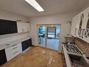uma cozinha com armários brancos e um forno com placa de fogão em Vila 12 em Cornetu