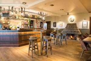 un bar avec tabourets et cheminée dans un restaurant dans l'établissement Waggon and Horses, Eaton, Congleton, à Eaton