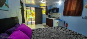 Habitación con cama con almohadas moradas y cocina. en Cabina Azul in Bejuco Beach with queen bed but no air conditioning, en Bejuco