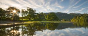 a view of a lake with trees and the sun at Hoglet Cottage in Carlisle