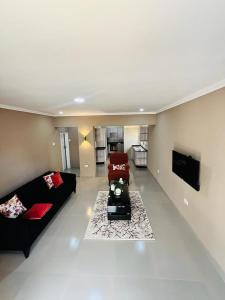 a living room with a black couch and a red chair at Goldland Apartments Annex in Kitwe