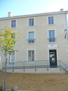 - un grand bâtiment blanc avec un balcon en face dans l'établissement Hotel Le Saint Aubin, à Chevillé