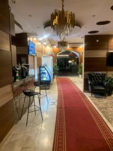 a lobby with a red carpet and chairs and a chandelier at الفخامة الجنوبية للشقق المخدومة in Jazan